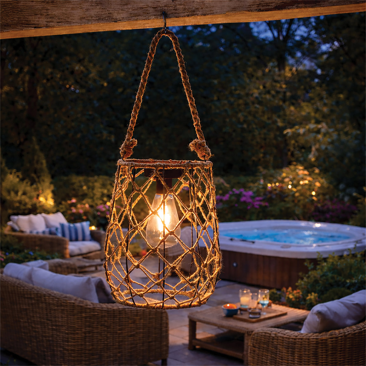 Decorative hanging lantern with a warm glow in an outdoor setting with a hot tub and seating area.